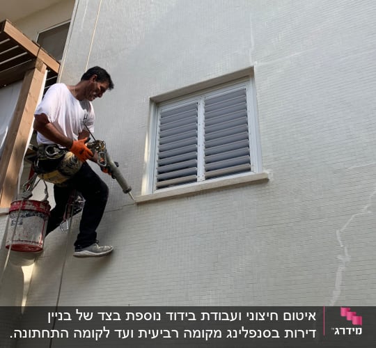 אדם על חבל עובד על קיר עם כלי עבודה